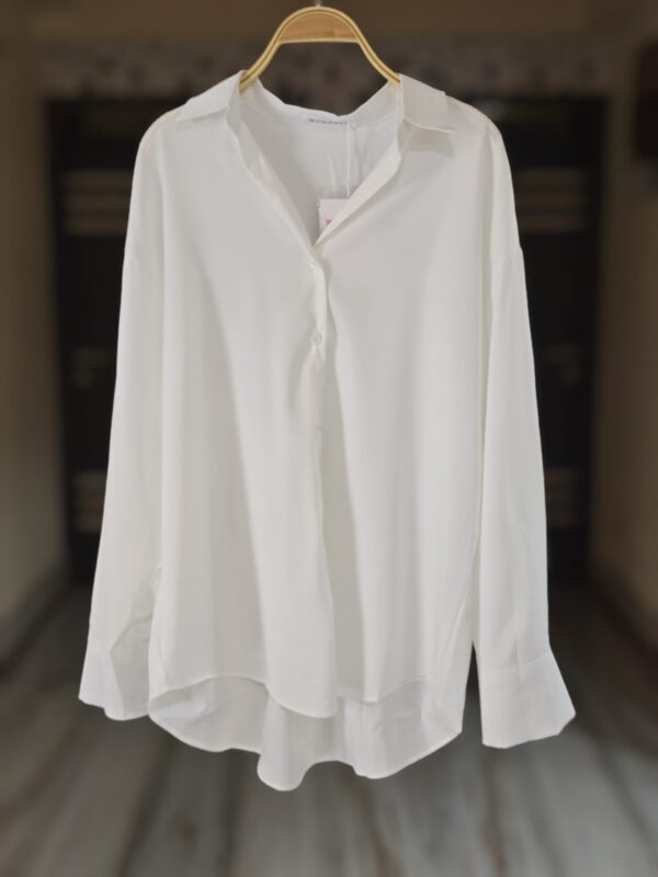 A timeless white button-down shirt made from lightweight fabric with a relaxed fit and a flattering high-low hem. Perfect for work, casual days, or layering.